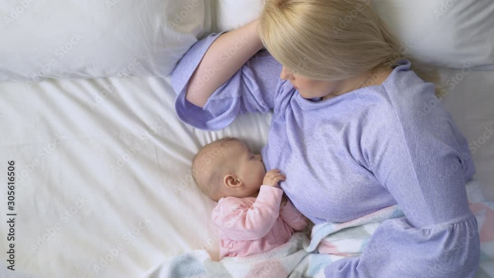 Young mommy breastfeeding beloved baby during daytime nap, natural nutrition Young mommy breastfeeding beloved baby during daytime nap, natural nutrition