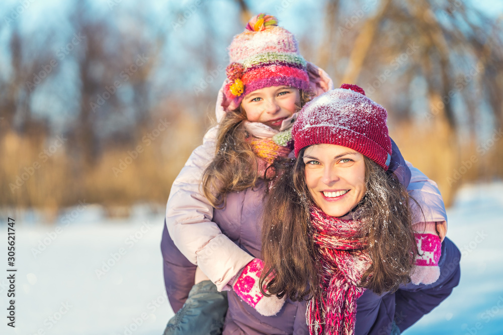 Little girl and her mother playing outdoors at sunny winter day. Active winter holydays concept.