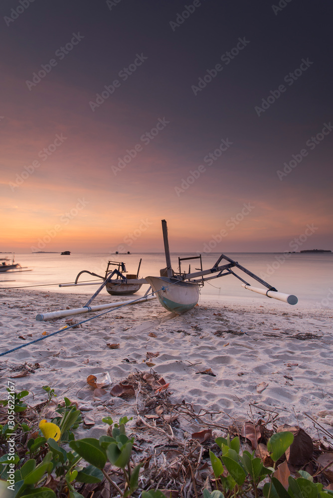 a boat with a beautiful sunset on lombok beach