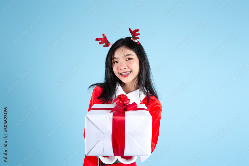 Happy Asian in Santa Claus costume holding Christmas gift box on blue background. Happy Asian in Santa Claus costume holding Christmas gift box on blue background.