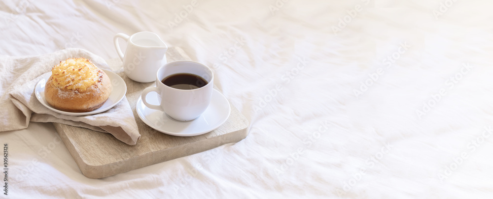 Morning Breakfast In Bed ,  cup of coffee and sweet bun on wooden tray on beige white sheets. Good morning scenery large background for banner.Copy space