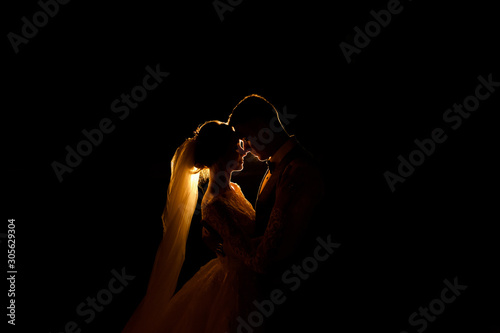Creative idea of wedding photography at night. Silhouette of a bride and groom illuminated by a lights photo