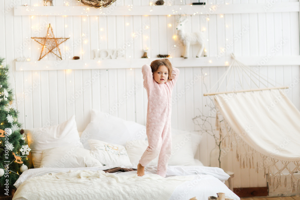 child in warm pajamas jumping on bed in bedroom child in warm pajamas jumping on bed in bedroom