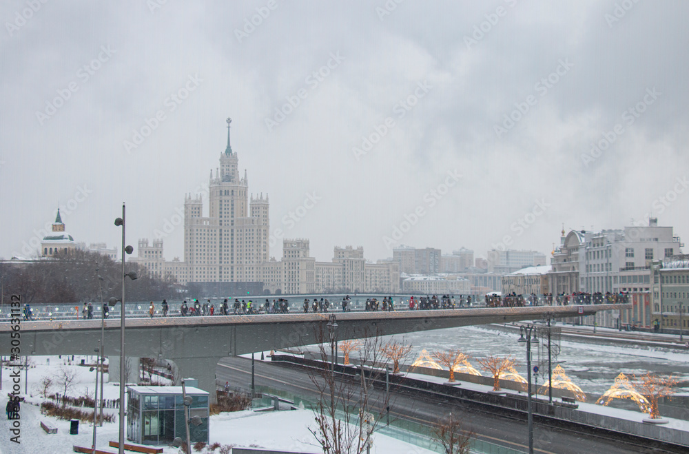 Tourists walk on a bridge over a river in Moscow. Zaryadye in a ziny foggy morning.
