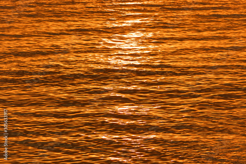 Golden glisten of sunlight reflects on the sunset sea surface