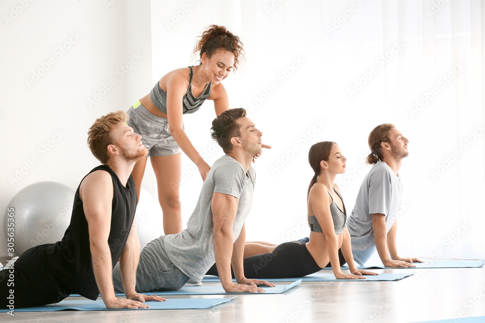 Group of people with instructor practicing yoga in gym Group of people with instructor practicing yoga in gym