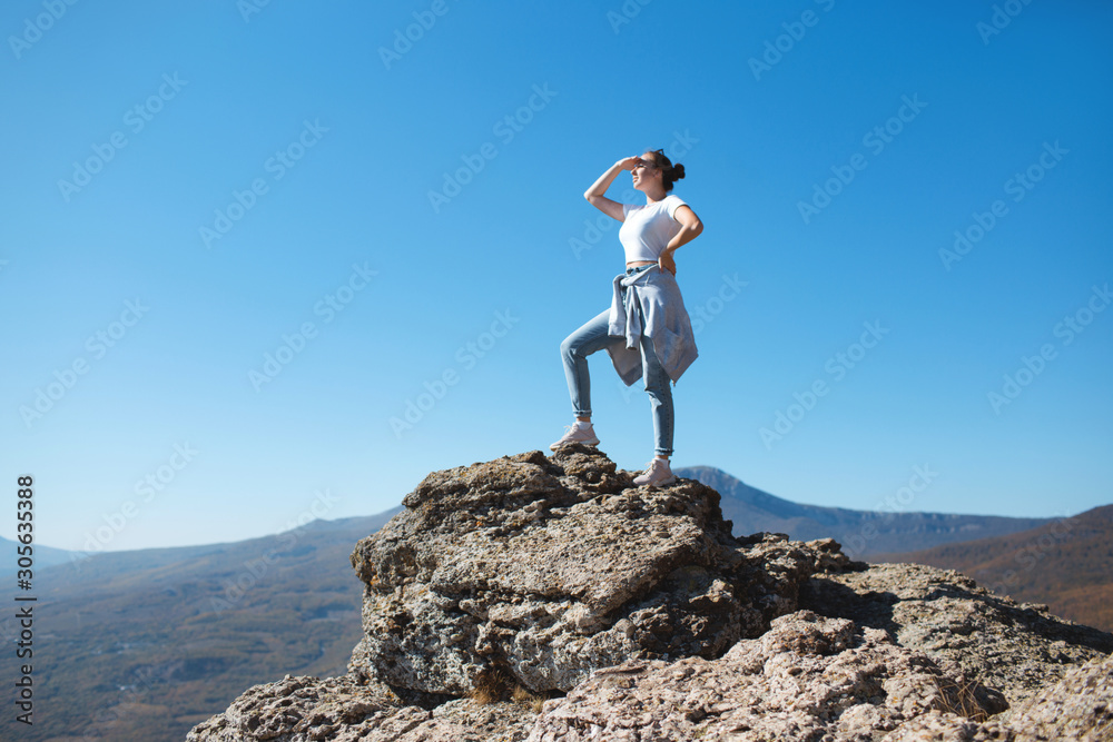 Obraz premium A girl with a backpack sits on a rock in the mountains and enjoying view of nature. Nature background. Journey. A trip to the mountains.