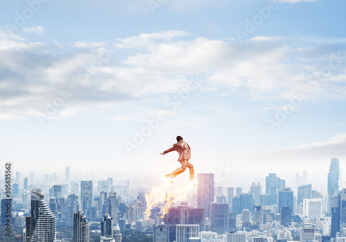 Businessman in suit and aviator hat flying in sky