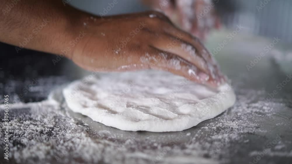 man thresh flour on stainless surface, prepare to make homemade style pizza man thresh flour on stainless surface, prepare to make homemade style pizza