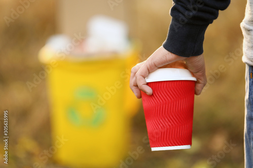 Little boy throwing out paper cup in trash container outdoors, closeup. Concept of recycling