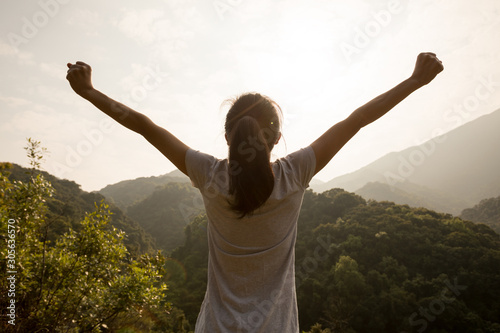 Cheering happy woman enjoying the view on morning mountain valley