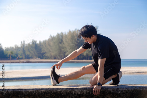 Asian male is stretching before doing work out ,jogging at seaside in the moring with beautiful sea view