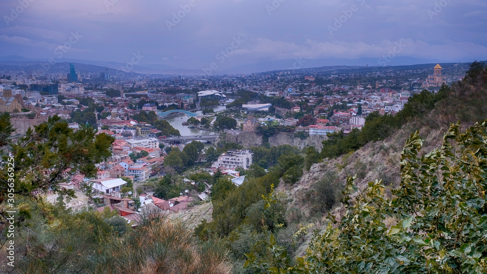 Panorama  view city of Tbilisi in cloudy weather from the surrounding mountains in autumn evening   during sunset time