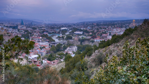 Panorama view city of Tbilisi in cloudy weather from the surrounding mountains in autumn evening during sunset time