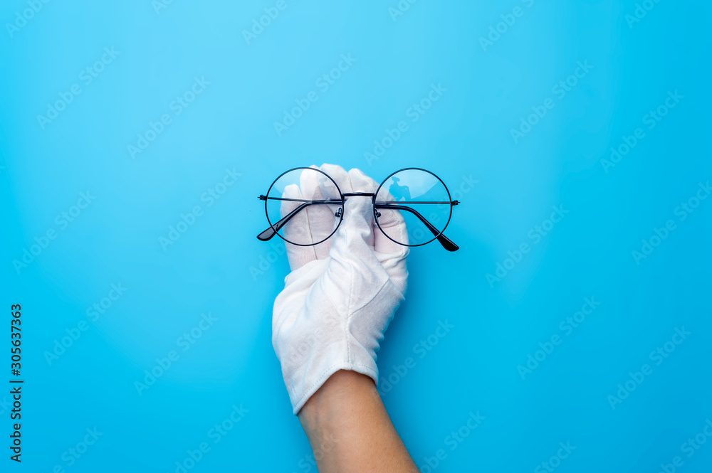 Hands in gloves are holding designer sunglasses