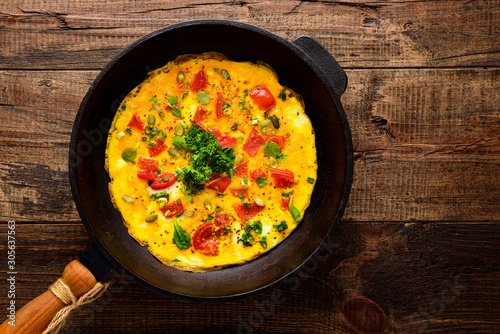 closeup omelet with old cast iron pan on wooden background with copy space
