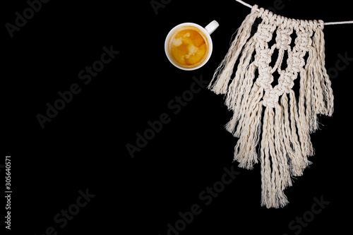 White macrame next to a cup of coffee with foam on a black isolated background. photo