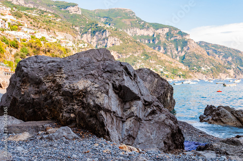 Big boulders lying on the beach, people resting, sunbathing and swimming in Tyrrhenian sea in Positano amazing medieval city on rocky mountains in Campania photo