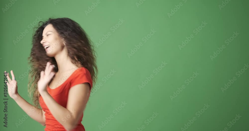 Excited young woman dancing over green background Excited young woman dancing over green background