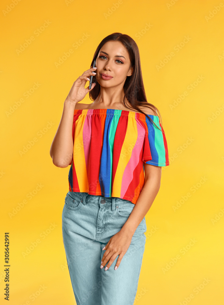 Beautiful young woman talking by phone on yellow background Beautiful young woman talking by phone on yellow background