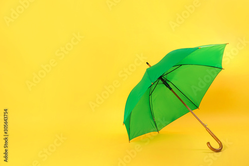 Beautiful green umbrella on light yellow background. Space for text