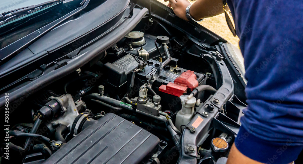 Hand of technician checking out and do a maintenance on the car engine outdoor.