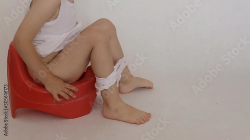 Little girl sits on a red pot. Accustoming to a toilet of children, background, hygiene