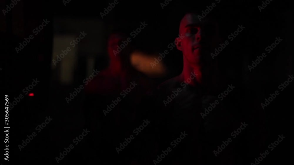 Two muscular firefighters doing biceps exercises in the light of blinking fire truck emergency lights at night. Close view Two muscular firefighters doing biceps exercises in the light of blinking fire truck emergency lights at night. Close view