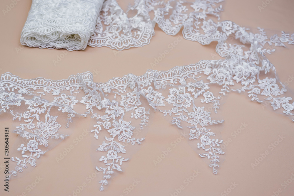 Texture lace fabric. lace on white background studio. thin fabric made of yarn or thread. a background image of ivory-colored lace cloth. White lace on beige background. Texture lace fabric. lace on white background studio. thin fabric made of yarn or thread. a background image of ivory-colored lace cloth. White lace on beige background.