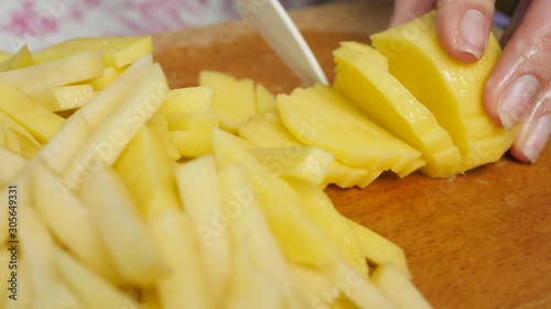 Woman at kitchen cutting thin slices of raw potato by knife. Dishes with vegetables. Concept of cooking and healthy eating