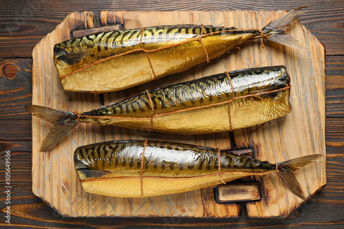Tasty smoked fish on wooden table, top view