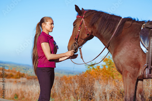 young beautiful girl strokes horse