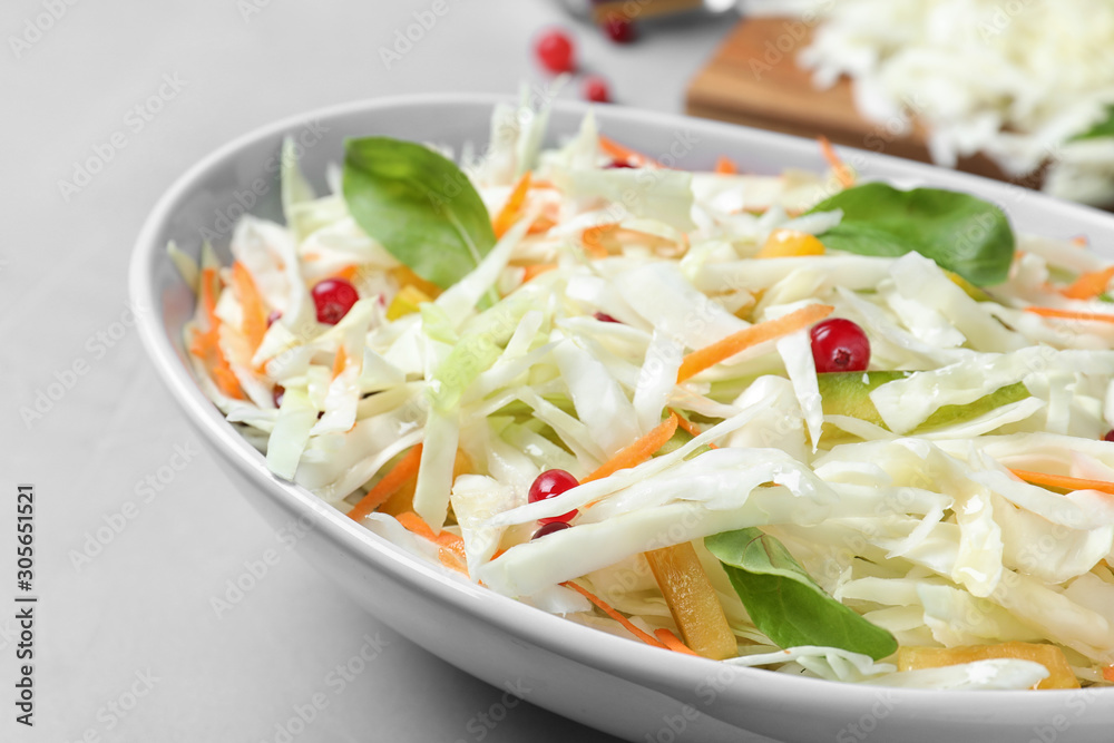 Fresh cabbage salad served on light grey table, closeup