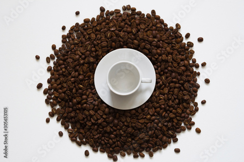 white cup on coffee beans on a white background  top view