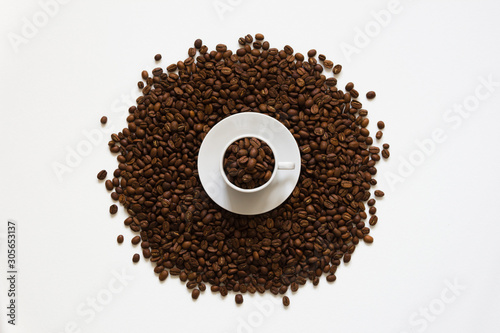 white cup on coffee beans on a white background, top view