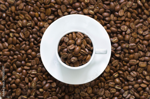 white cup on coffee beans on a white background, top view