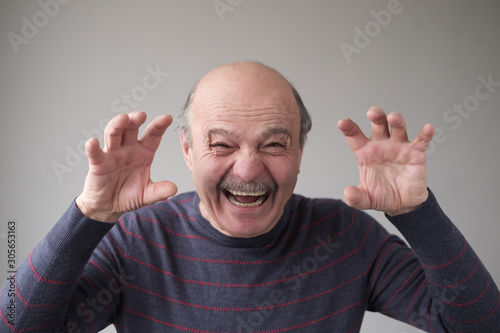 Fotografia Senior hispanic man with creepy face grimacing to scare you