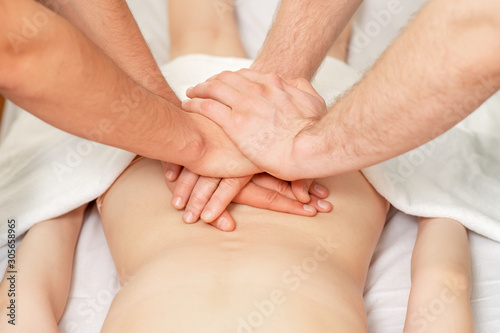 Two male masseuses doing a massage with four hands for woman close up.
