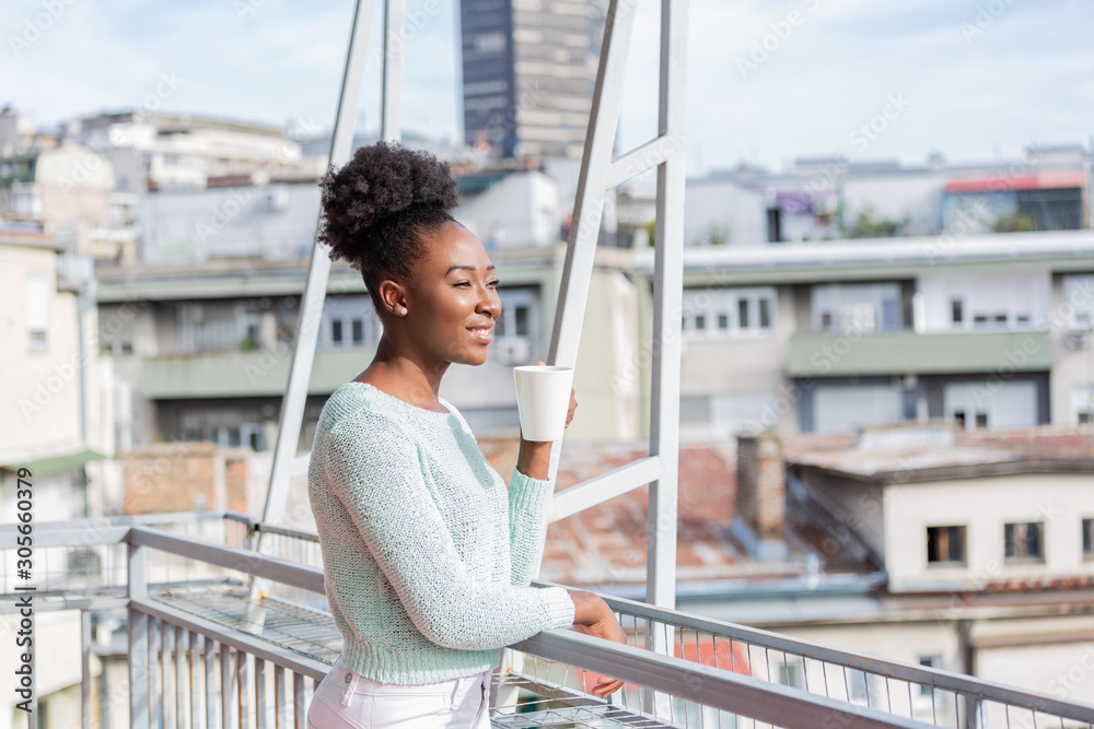 Portrait of a happy african american black woman thinking and looking away with coffee on vacation with a resort or hotel with city view in the background Portrait of a happy african american black woman thinking and looking away with coffee on vacation with a resort or hotel with city view in the background
