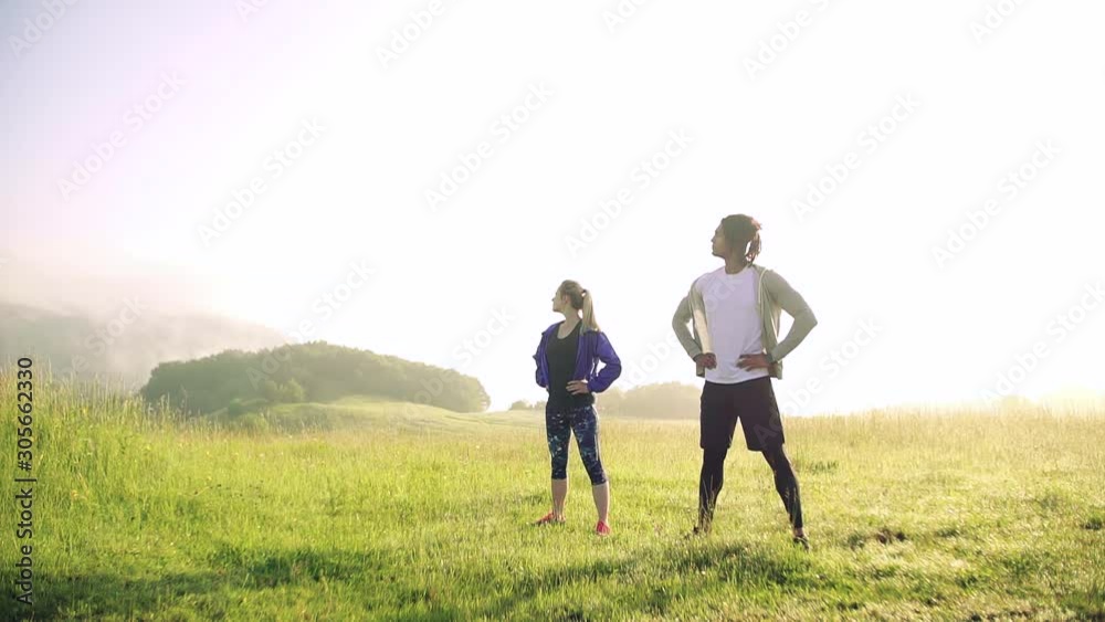 Young couple doing exercise on meadow outdoors in nature early in the morning. Young couple doing exercise on meadow outdoors in nature early in the morning.