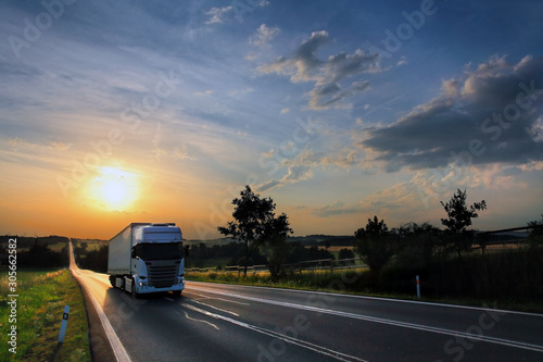 White truck transport on the road and cargo at sunset