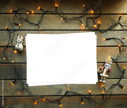 Christmas Moke up. White blank paper, garland and Christmas hand-made toys on the wooden table background. 