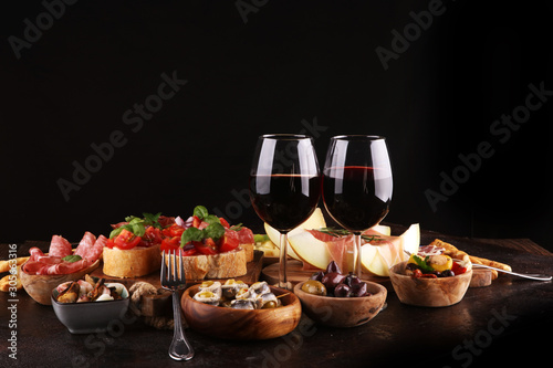 Fototapeta Naklejka Na Ścianę i Meble -  Italian antipasti wine snacks set. Cheese variety, Mediterranean olives, seafood salad, Prosciutto di Parma, tomatoes, anchovy and wine in glasses