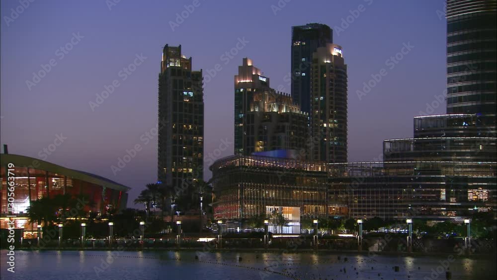 Medium low-angle night still shot of bright orange coloured Dubai Opera building, and boats sailing on water, Dubai, UAE Medium low-angle night still shot of bright orange coloured Dubai Opera building, and boats sailing on water, Dubai, UAE