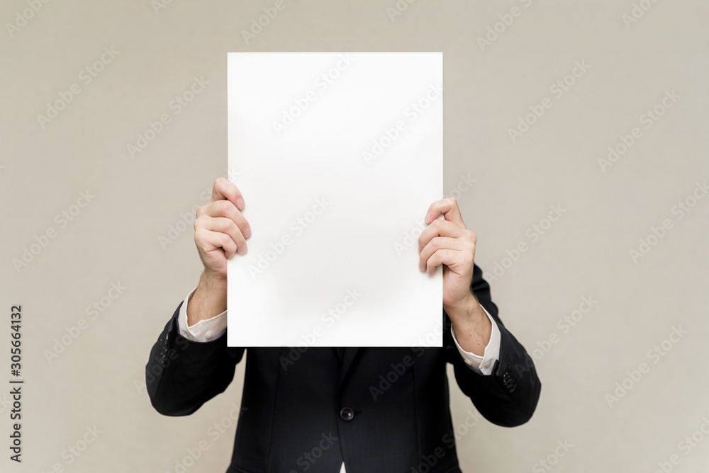 a man in a suit holds a white sheet in front of him. man hiding behind a poster. the man on the face of the white pattern copy space a man in a suit holds a white sheet in front of him. man hiding behind a poster. the man on the face of the white pattern copy space