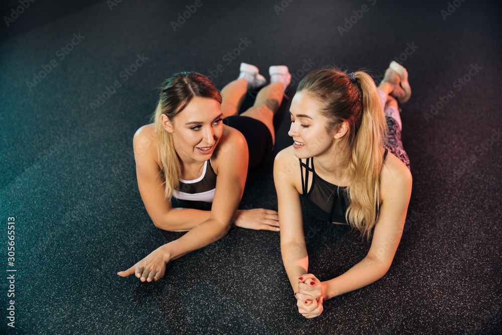 Fototapeta premium young couple sitting on bench,Young sports girls are engaged in fitness, lifestyle, sports and healthy eating, in the gym girls do exercises