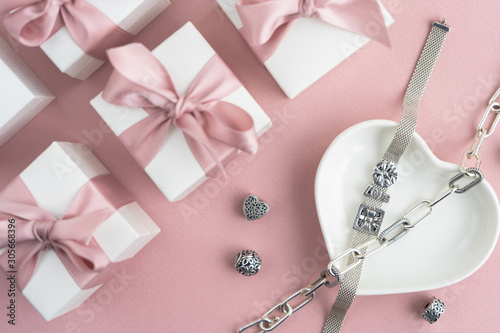 Gift boxes wiyh powdery ribbon. Powdery background. Silver bracelet with charms. Gift box for the New Year and Christmas. Best gift for Valentines Day and Mothers day. photo