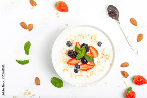 Greek yogurt with granola fresh strawberries, blueberries, blackberries and almonds on white table. Healthy snack. Breakfast food. Top view, copy space.