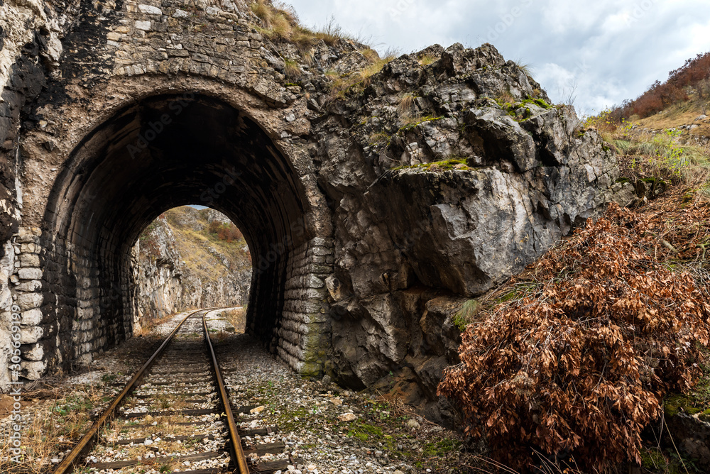 Old abandoned railway passing through short tunnels in picturesque rural scenery