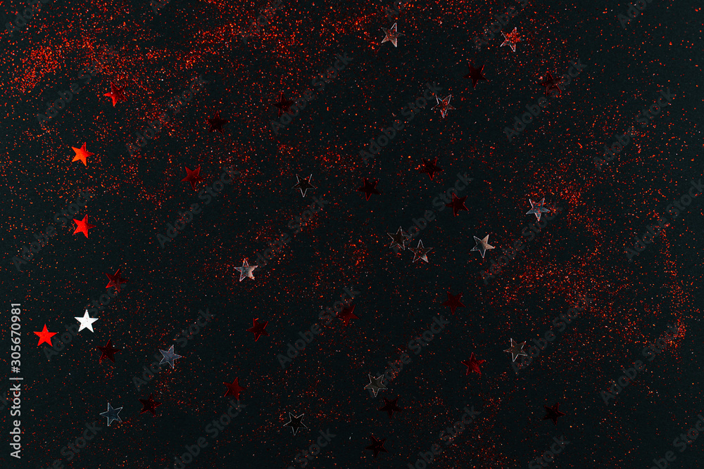 Red and silver sparkles and stars on black backdrop. Holiday concept. Red and silver sparkles and stars on black backdrop. Holiday concept.